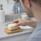 Man picking up soap from a Taro Non-Slip Bamboo Soap Holder on a wooden tray by the sink.