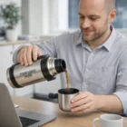 Smiling man pours coffee from a Devon Vacuum Flask into a metal cup.