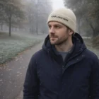 Man wearing a Cleo Merino Wool Beanie and dark jacket on a foggy autumn park path.