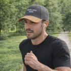 Man jogging, wearing Amico Six Panel Caps with YOUR LOGO HERE and wireless earbuds.