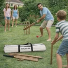 A family plays cricket on grass with Arnhem Cricket Sets and a bag nearby.