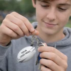 Teen holding Riverina Rugby Ball Key Rings labeled YOUR LOGO HERE with keys attached.