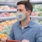 Man in denim shirt wears a Pyrenees Linen Face Mask in a grocery store produce aisle.
