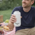 Man holding a 500ml Camelbak Horizon Can Cooler Mug with YOUR LOGO HERE at a picnic.