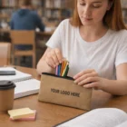 Woman takes colored pencils from a Kimberley Kraft Pencil Case labeled YOUR LOGO HERE at library.