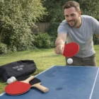 Man playing outdoor table tennis with Excella Portable Table Tennis Sets and YOUR LOGO HERE bag.