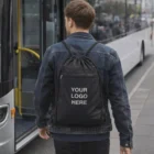 Person with a Trekker Nylon Drawstring Backpack labeled YOUR LOGO HERE boarding a bus.