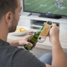 Man opens a beer with a Calfi Magnet Bottle Opener while watching football on TV.