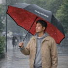 Man holding a Clovis Twin Layer Classic Umbrella with YOUR LOGO HERE in the rain.