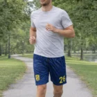Man jogging in a park, wearing a gray shirt and Men's Soccer Shorts numbered 26.