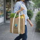 Person carrying groceries in a Collier 23L Kraft Tote on a bustling city sidewalk.