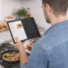 Man cooks, reading a recipe on a Tablet Case With Grip And Stand in the kitchen.