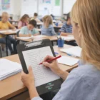 Teacher grading papers with a red pen as students use Translucent Clipboards With Rulers.