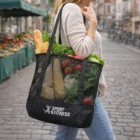 A woman carries groceries in a Mesh Sports Tote Bag on a city street.