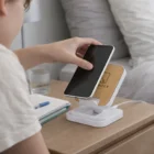 Placing a phone on a Wireless Charging Stand on the bedside table.
