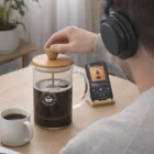 Someone brews coffee with an 850Ml Coffee Plunger while listening to a podcast on their phone.