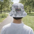 Person wearing our Tie Dye Bucket Hat with a colorful graphic in a sunny park.