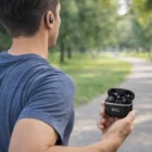 Man jogging in a park, wearing TWS Earbuds 2.0 and holding the open charging case.