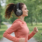 Woman jogging outdoors in a coral top, wearing Wireless Headphones V3, side view.