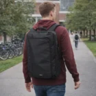 A person in a maroon hoodie walks outside with a large 21L Convertible Backpack.
