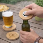 Person using Round Bottle Opener Coasters with beer and chips outdoors.