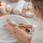 Woman enjoys spa bath with 4-In-1 Pedicure Tools, pumice stone, candles, and towels nearby.