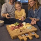 Smiling family enjoying Rectangle Cheese Boards with meats and grapes on the couch.