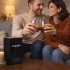 A smiling couple toasts with the Dusk Whiskey Glasses Set Of 2 on a couch near a keepsake box.