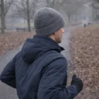 Jogger in park on a cold day wearing Deluxe Heather Beanie and a dark jacket.