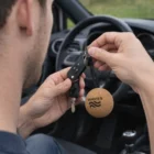 Person holding car keys with a Cork Key Ring labeled WAVES inside a car.