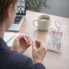 Person filing nails at a desk with Sophie Manicure Sets, coffee, and a laptop nearby.
