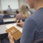 Student taking notes in class with a Recycled Cover Notebook.