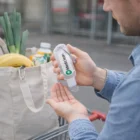 Person uses Mohave Hand Sanitisers 55Ml by a grocery bag in an outdoor shopping cart.