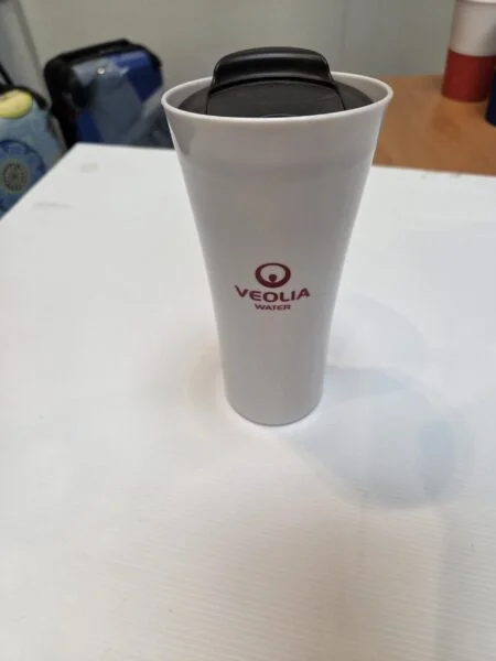 White travel mug with Veolia Water logo—perfect for universal event items or event gifts.