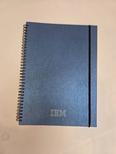 Blue spiral-bound IBM notebook with black band—perfect for event gift ideas, no size required.