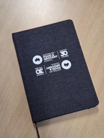 Black notebook with white Australian Food & Grocery Council logo for community event planning.