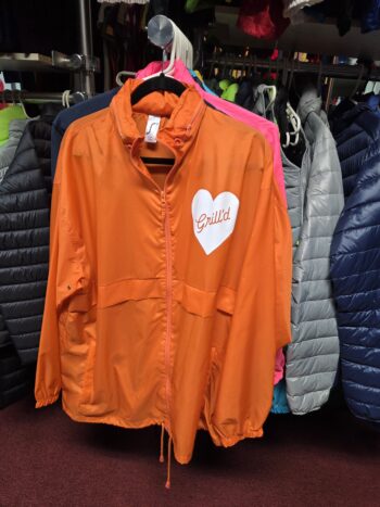 Orange unisex apparel jacket with a white heart and Grilld text, hanging on a rack.