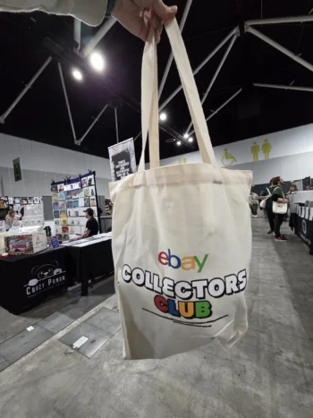 A hand holds an eBay Collectors Club tote bag—perfect for bulk orders at conventions.