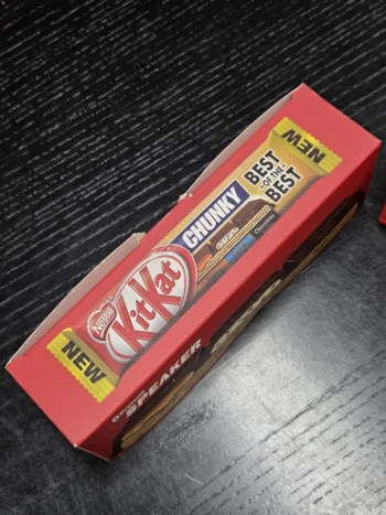 Red KitKat Chunky box on black wood, highlighting printing differences on packaging logos.