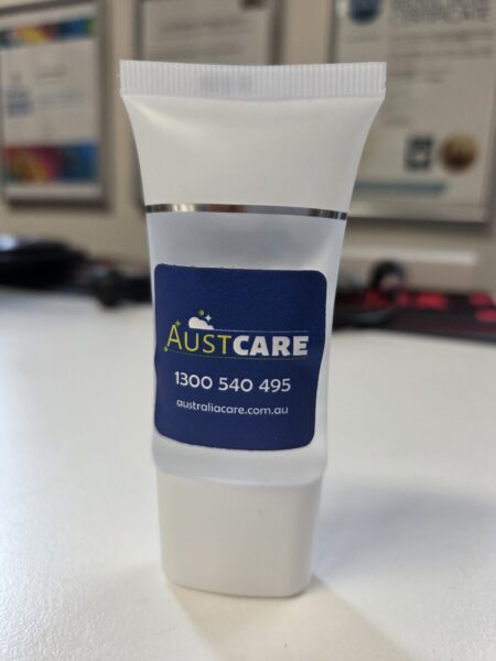 Small white Austcare tube with logo—ideal branded merchandise to reduce reprints and logo errors.