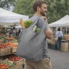 Man with a gray Ashton Recycled Large Shopper Tote holding vegetables at a farmers market.