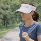 Woman jogging in a blue shirt and wearing a Corporate Sports Event Visor.
