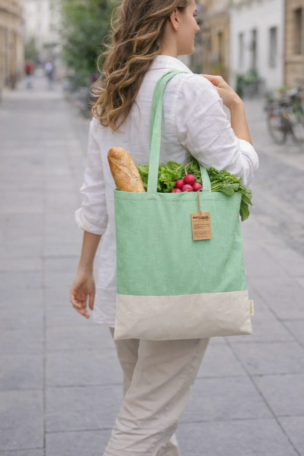 Woman carrying Recycled Cotton Skadi Eco Bag with groceries on a city street.