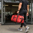Man in black sportswear with an Rpet Sustainable Duffle Bag enters a fitness center.