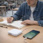 Man writes at his desk, charging his phone with Abs Power Banks.