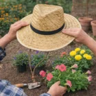 Person wearing the Braided Straw Hat W/Toggle while gardening among colorful flowers.