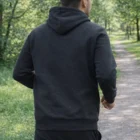Man in a Jb's Branded Hoodie walks on a forest path, viewed from behind.