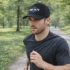 Man jogging in a park wearing a black Polycotton Dynamic Cap and a dark t-shirt.