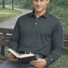 Man sitting on a bench reading, wearing Nike Long Sleeve Dri-Fit Stretch Tech Polo.