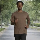Man jogs in Staple Organic Tees and black pants on a tree-lined street.